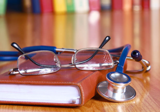 stethoscope on book with leather cover and glasses